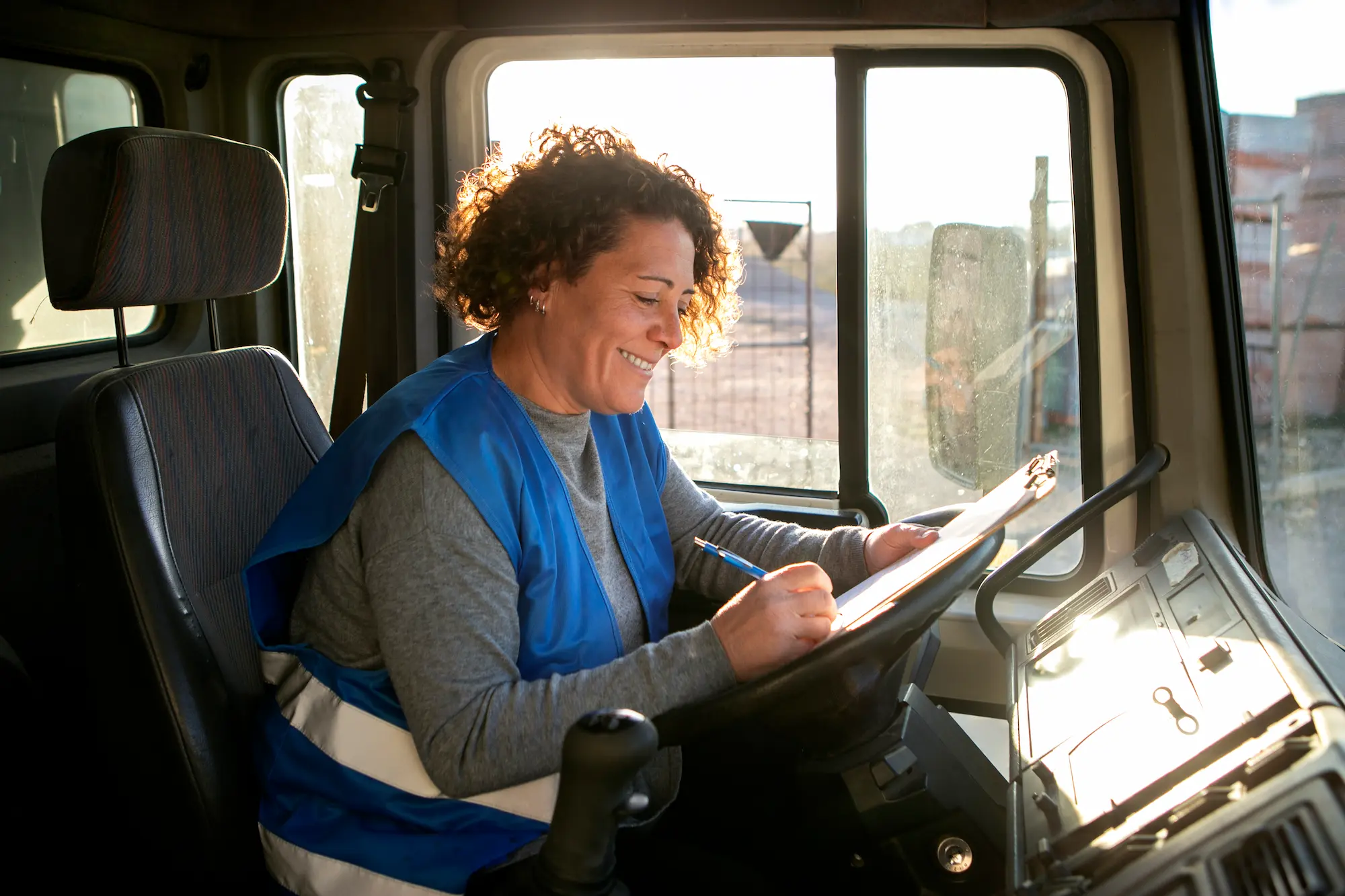 Female truck driver completing delivery paperwork inside vehicle for a trusted trucking company in Vancouver