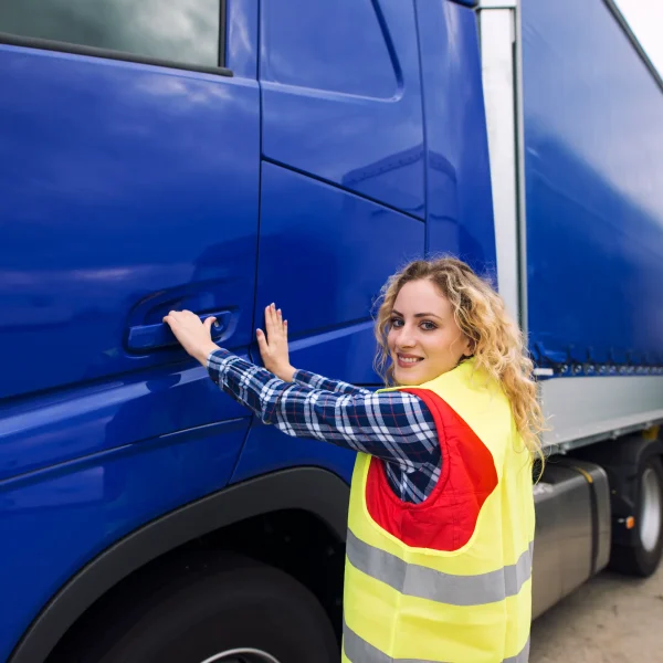 Professional driver entering semi-truck during Cross-border trucking Canada to USA freight transportation service at logistics yard