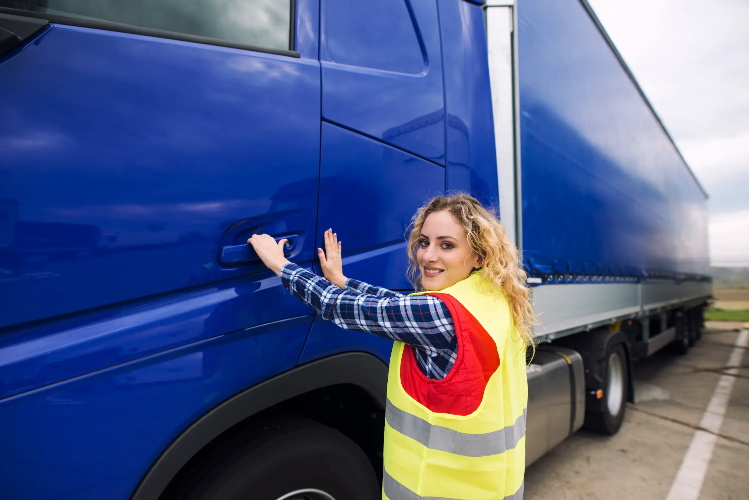 Professional driver entering semi-truck during Cross-border trucking Canada to USA freight transportation service at logistics yard