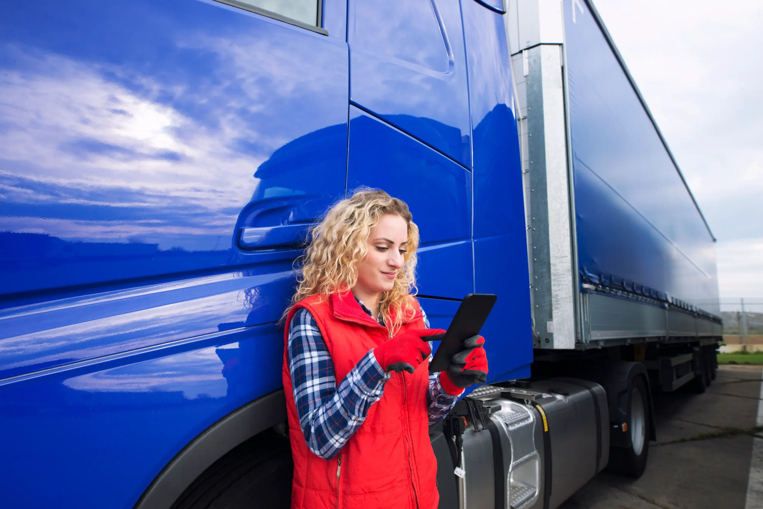 Female truck driver using tablet for route planning during Cross-border trucking Canada to USA freight transport service