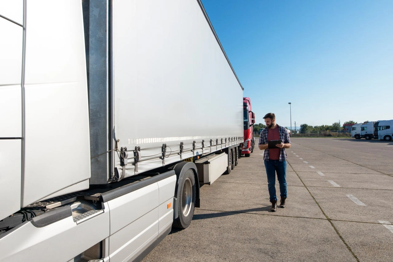 Logistics operator inspecting commercial freight truck at transport yard supporting professional shipping services Canada operations