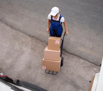 Warehouse worker transporting packaged freight on hand truck representing a reliable trucking company BC handling commercial shipments