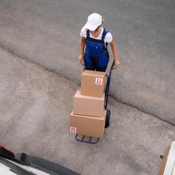 Warehouse worker transporting packaged freight on hand truck representing a reliable trucking company BC handling commercial shipments