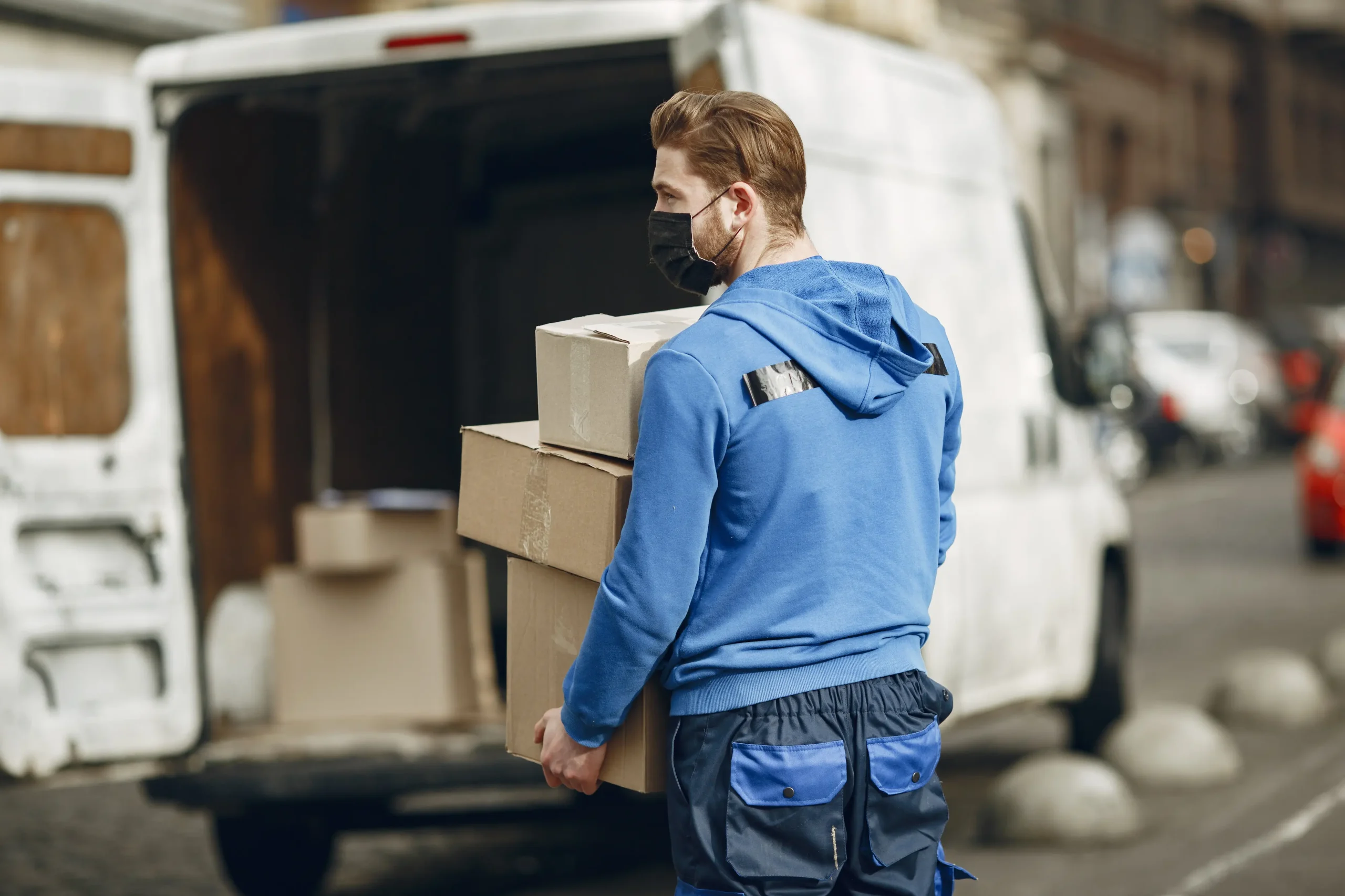 Delivery driver loading packages into van representing professional hauling company and efficient cargo handling services